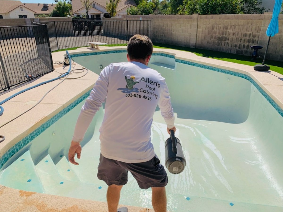 Allen's Pool Catering tech in a branded shirt working inside a drained pool
